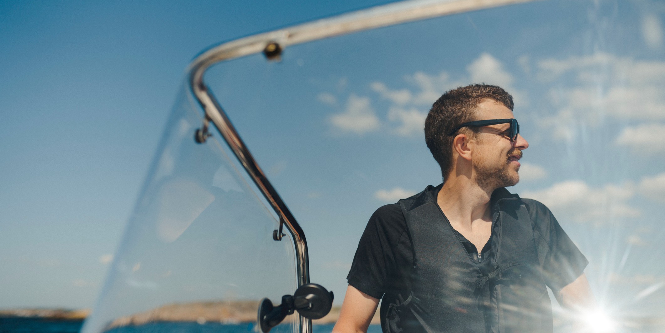 Glad man med flytväst på motorbåt