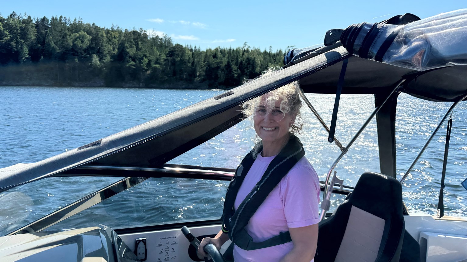 Glad kvinna med flytväst på motorbåt