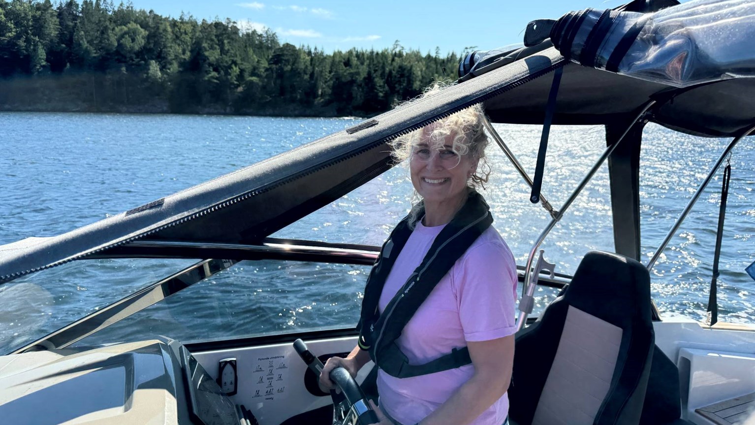 Helen kör sin motorbåt och ser glad ut
