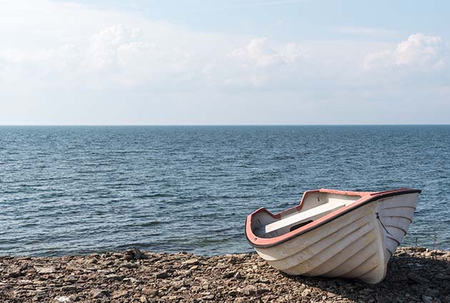 Liten båt som ligger på strandkant