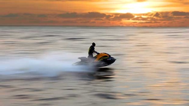 Vattenskoter på vattnet i solnedgången